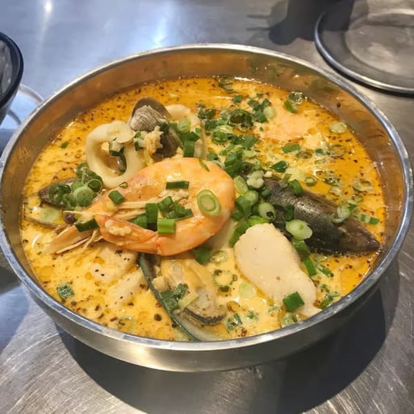 A metal bowl of Big T's Seafood Bar's seafood stew with shrimp, mussels, squid, and scallops.