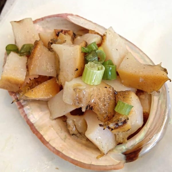 Big T's Seafood Bar's abalone dish, served in a shell with chopped green onions.